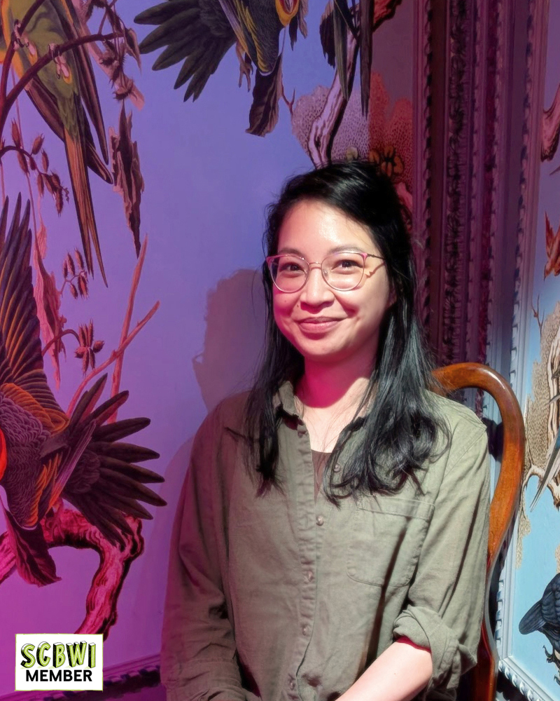 portrait of Denise Magdale smiling against a wallpapered background depicting birds and flowers
